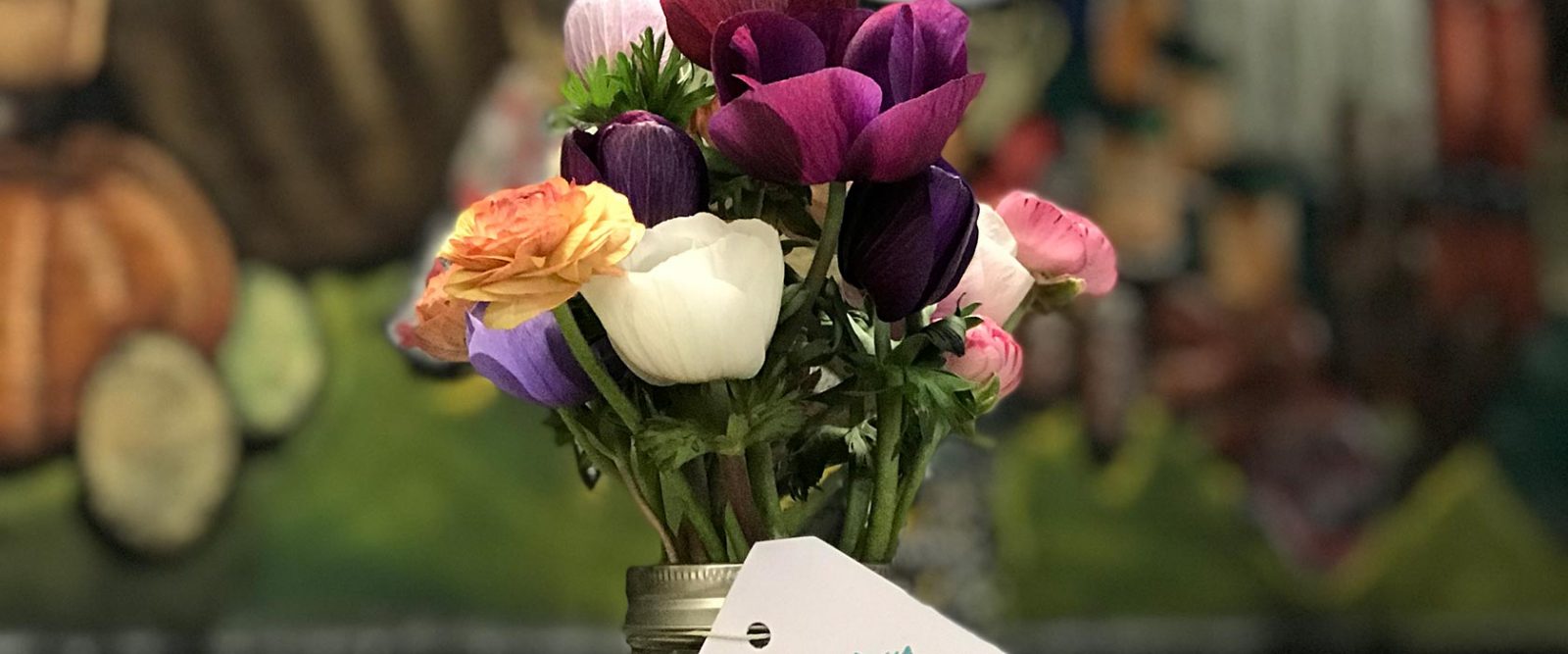 Arrangement of various flowers in vase on shop counter