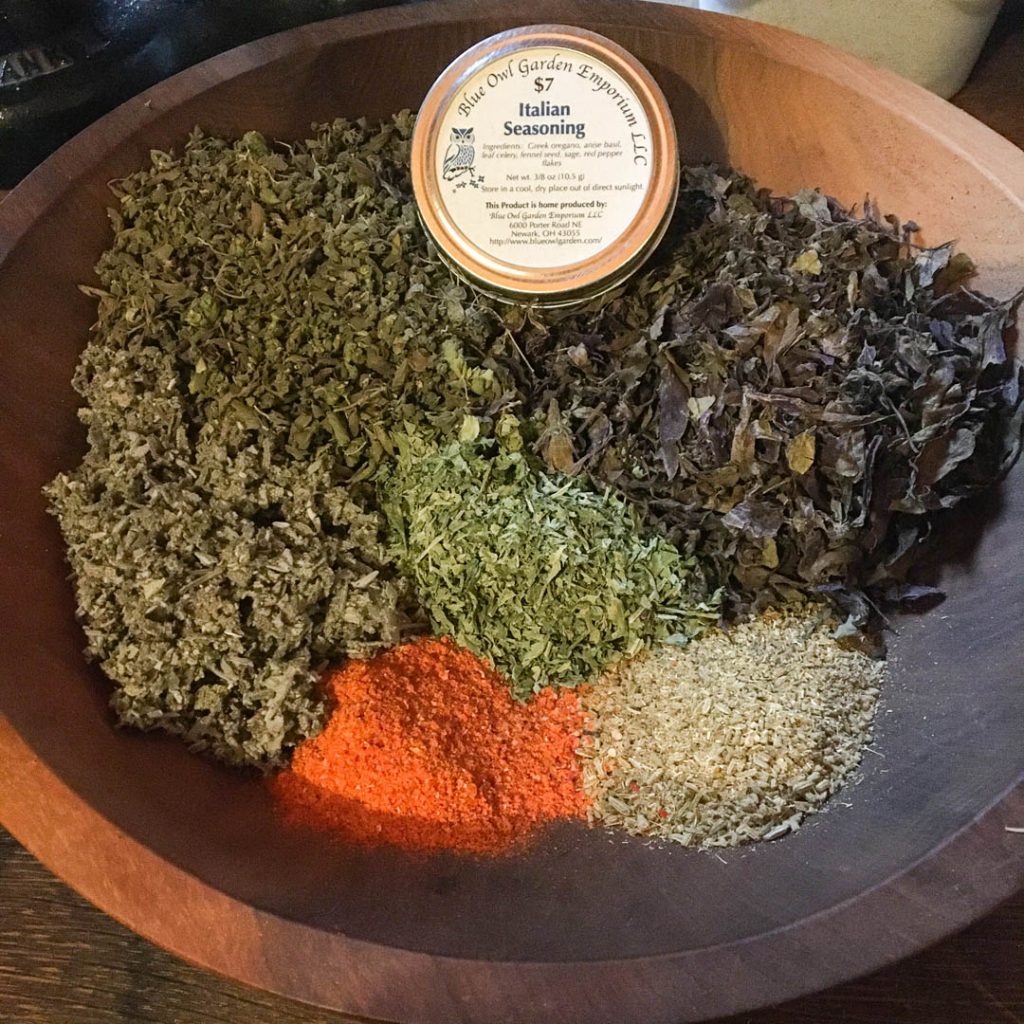 Tin of Blue Owl Caprilands spices sitting on dried spices in a large bowl