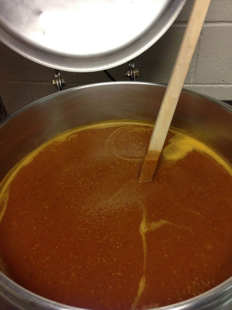 Large pot of spicy sauce with wooden spoon