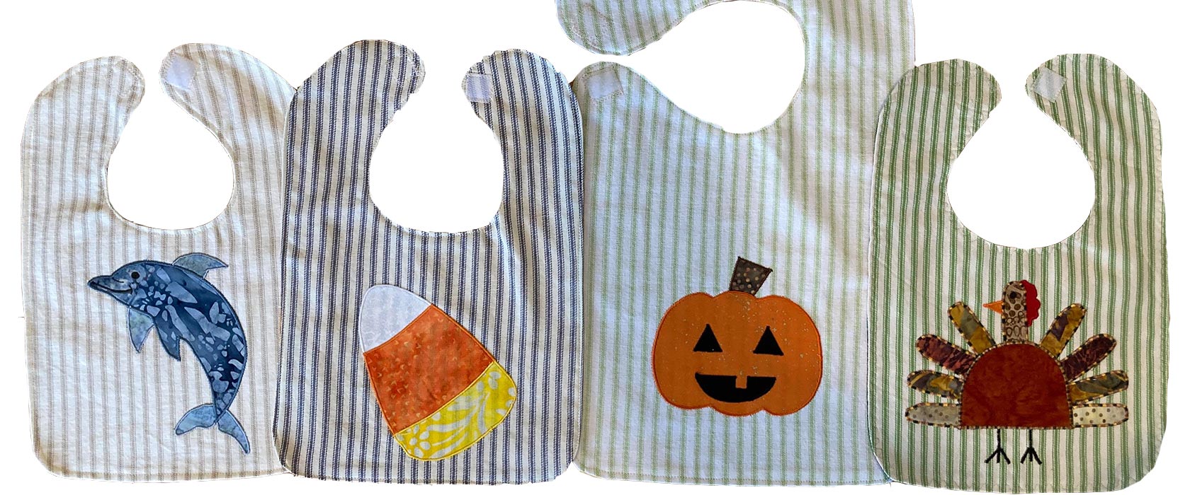 Four handmade appliqué baby bibs in fall motifs.