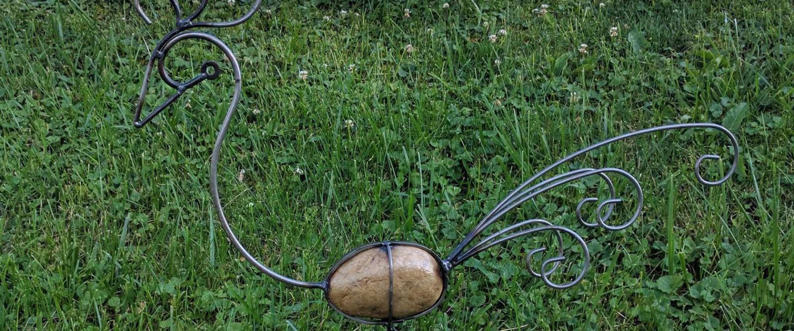 Metal bird sculpture on green lawn.