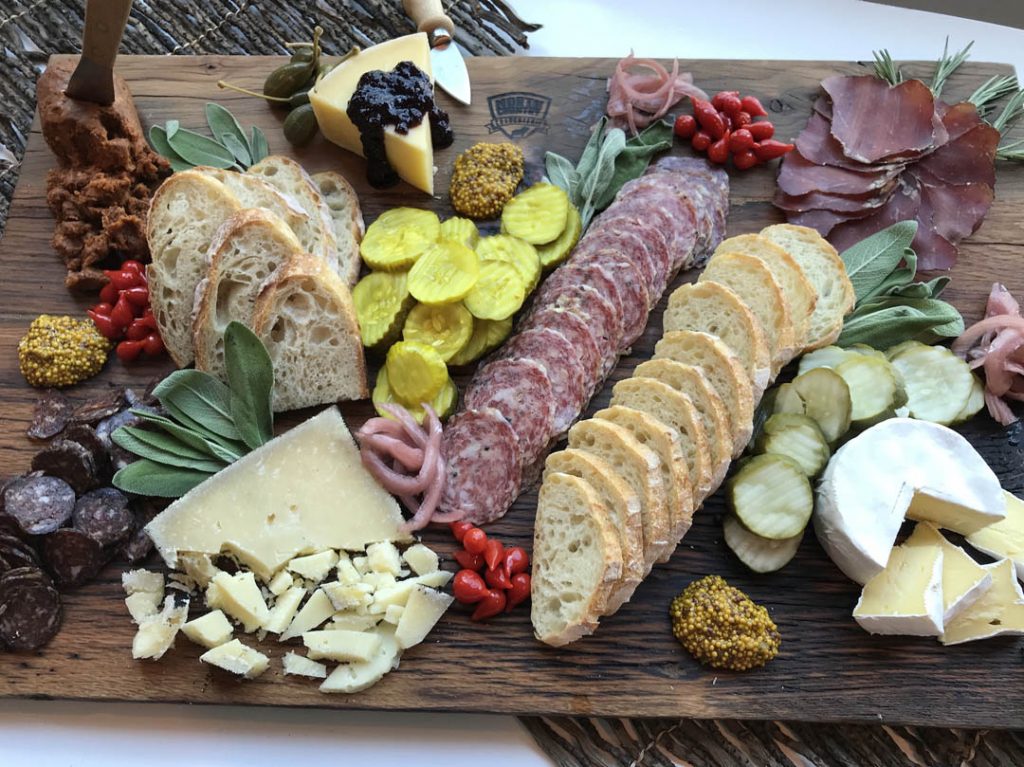 Large array of charcuterie meats, cheese, breads and vegetables.