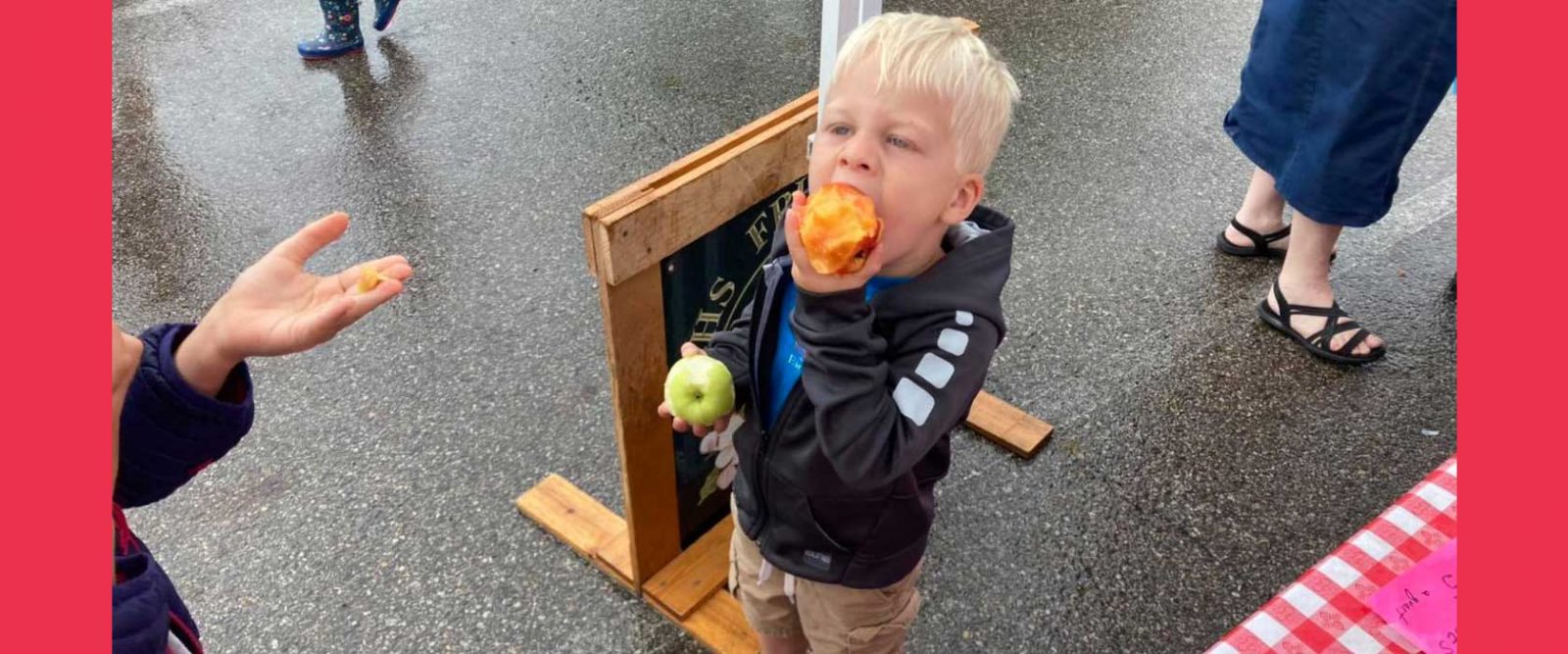 Small boy holding green apple in one hand and taking a bite out of a peach with the other