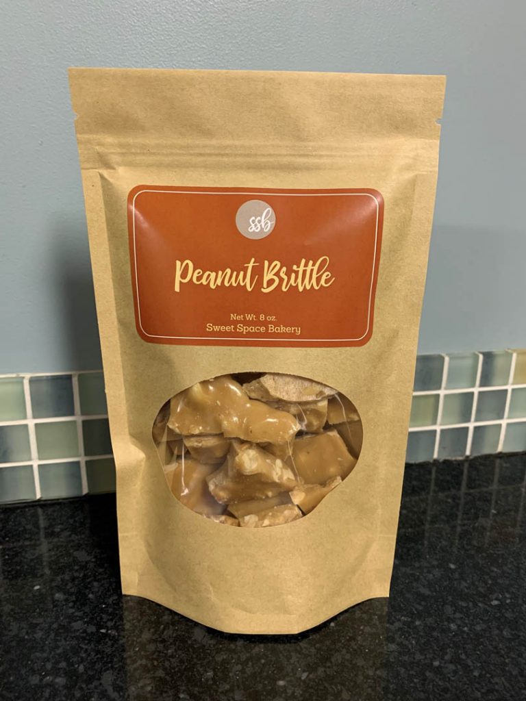 Kraft bag filled with Sweet Space Bakery Peanut Brittle.