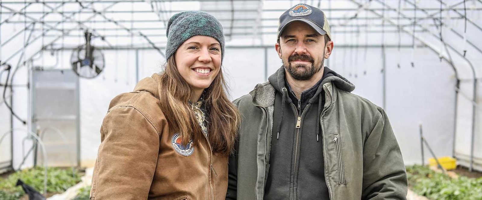 Farming couple standing inside their greenhouse