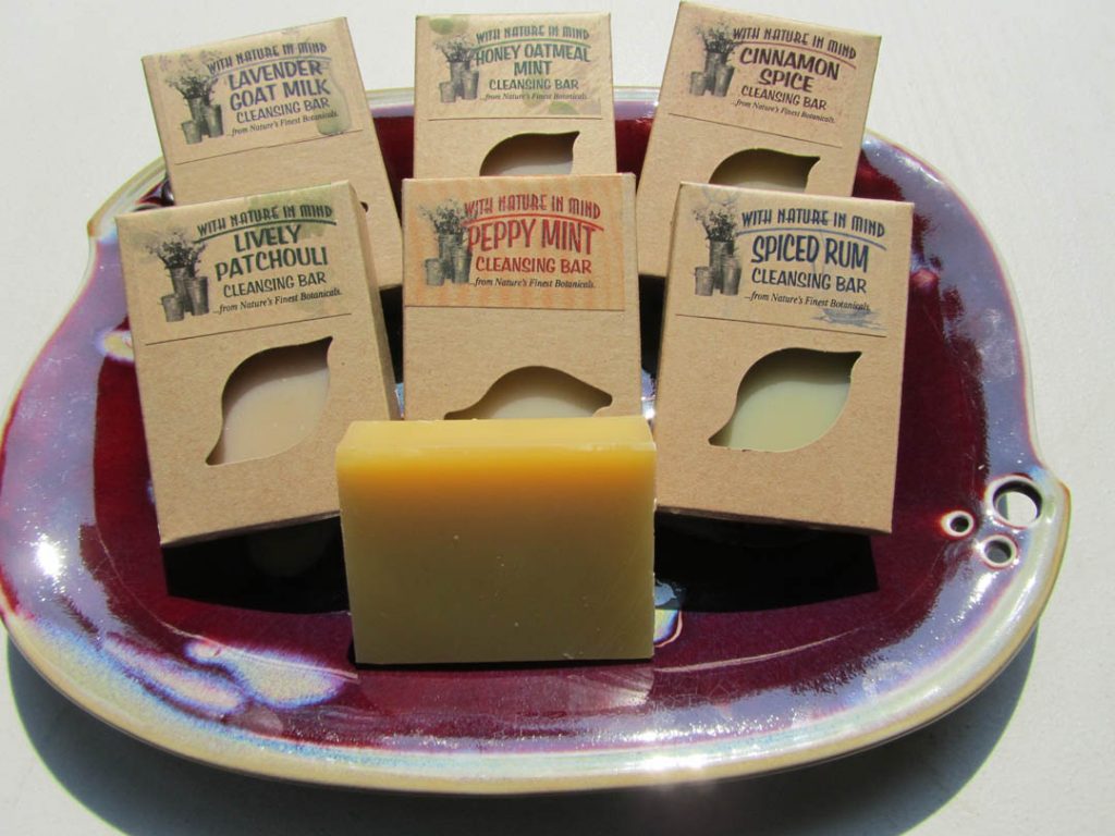 Array of half-dozen handmade soaps by With Nature In Mind displayed in ceramic dish.