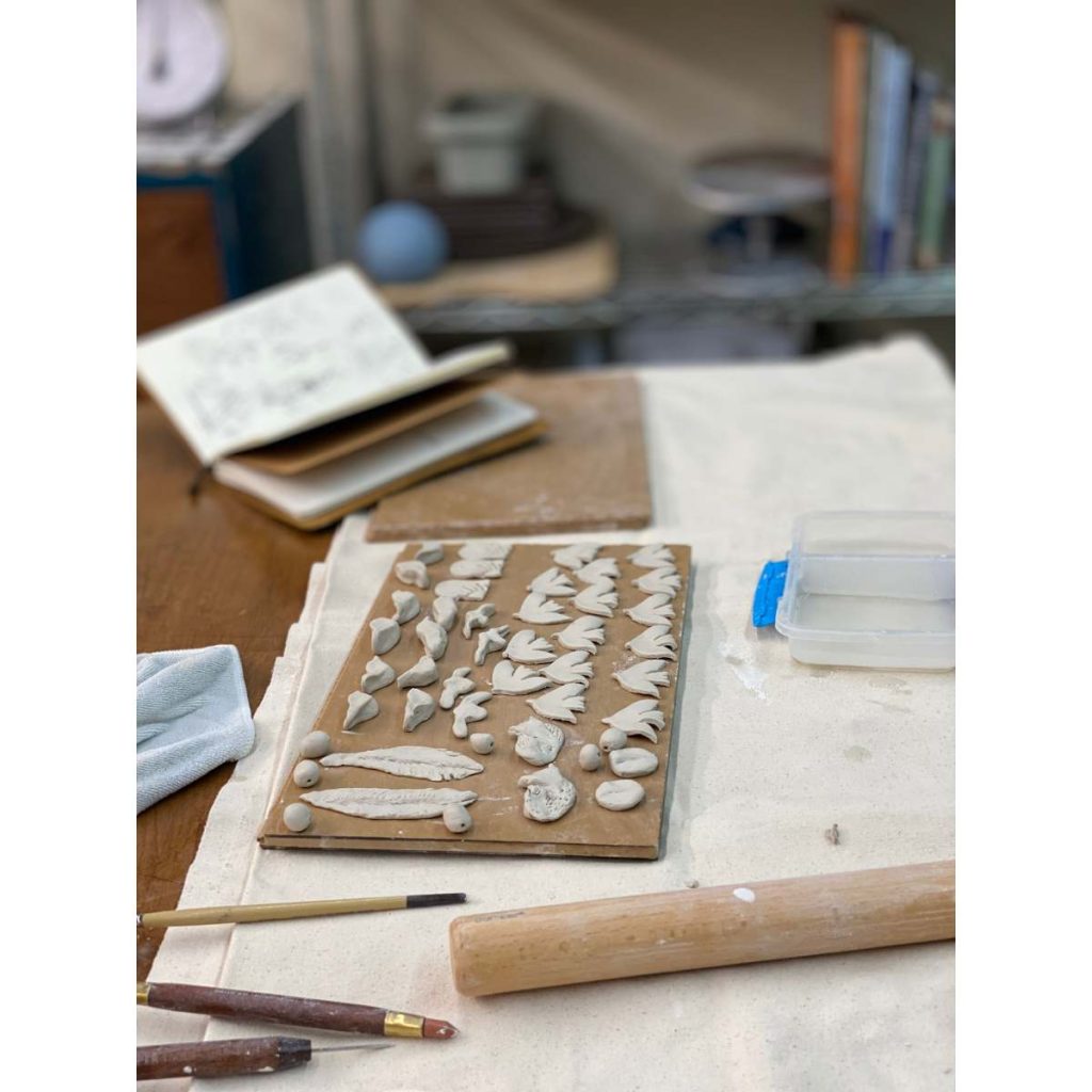 pottery studio table with tools and cut out shapes of clay