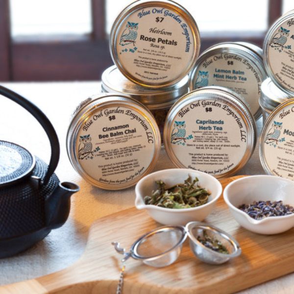 jars of herbal teas with black tea pot, dishes of loose tea and open tea ball