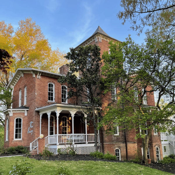 A brick Victorian manor house with porch and tower