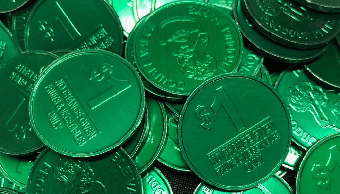 shiny round green tokens that say $1