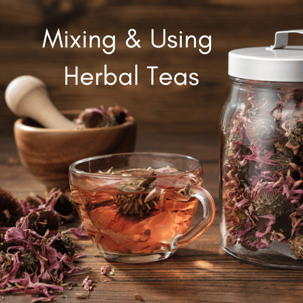 glass teacup with herbal tea and dried herbs, plus glass jar of dried pink herbs and wooden mortar and pestle