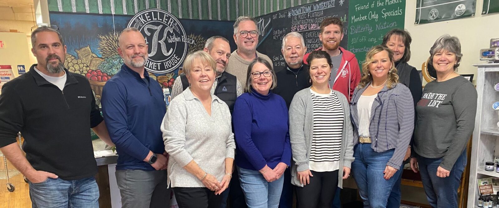 group of people posing for the camera in front of a market checkout area