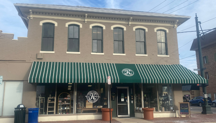 tan two story historic building with green and white striped awning