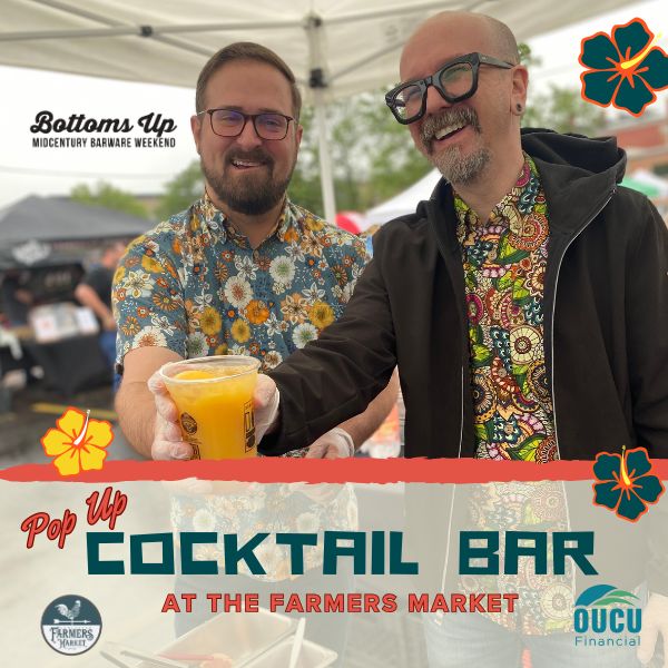 two smiling men in Hawaiian shirts handing over a fruity cocktail in a plastic DORA cup